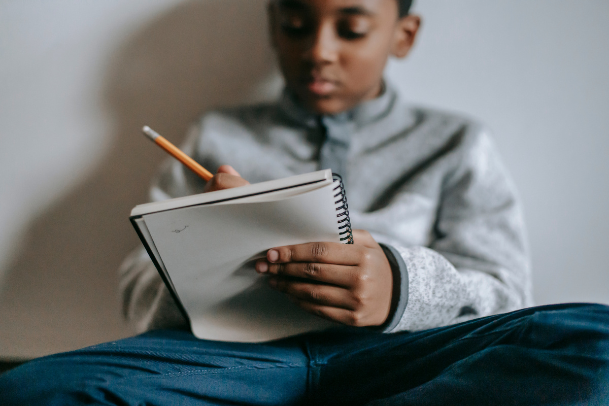 Focused black kid writing in notebook